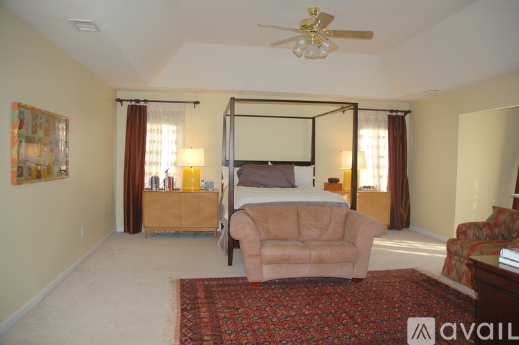 A bedroom with a bed, couch, and a ceiling fan.