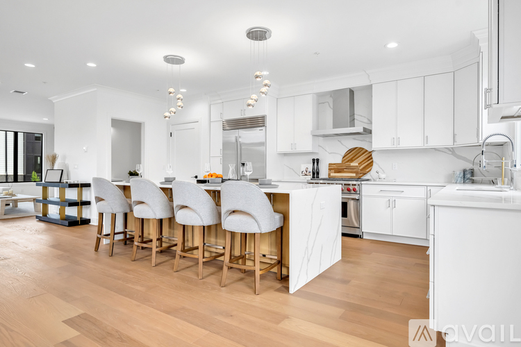 A kitchen with white cabinets and a wooden island with four chairs.