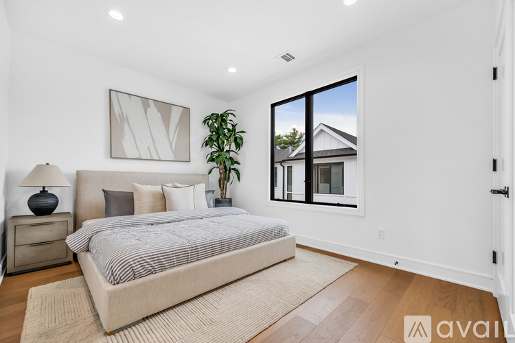 A bedroom with a large bed and a view of a house through the window.