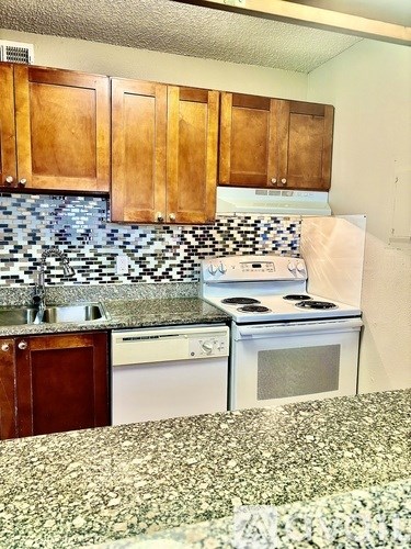 A kitchen with a white stove top oven and a white dishwasher.