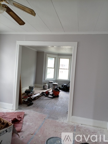 A room with a ceiling fan and a window is under construction.