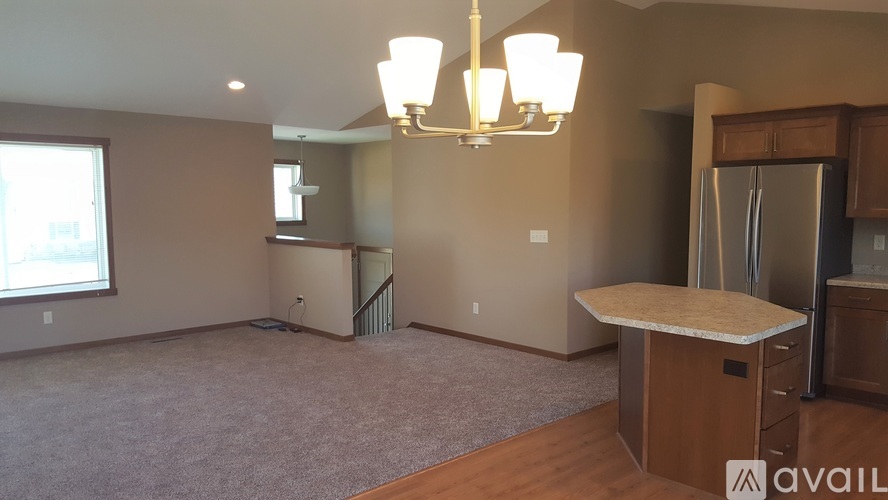 A living room with a carpeted floor, a wooden table, and a chandelier hanging from the ceiling.