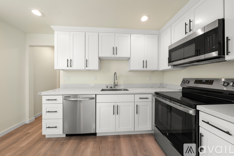 A modern kitchen with white cabinets and black appliances.