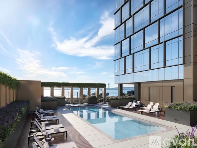 A modern building with a pool and lounge chairs.