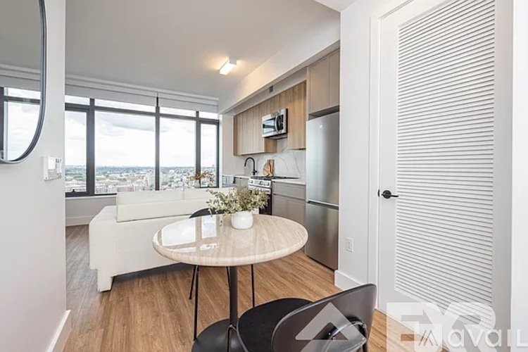 A modern kitchen with a table and chairs in the foreground and a view of the city through the windows.