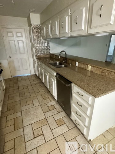 A kitchen with white cabinets and a tile floor.