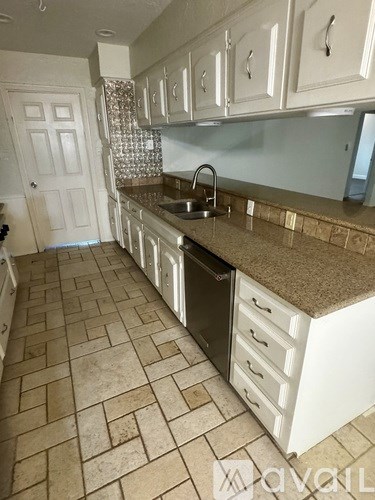 A kitchen with white cabinets and a tile floor.