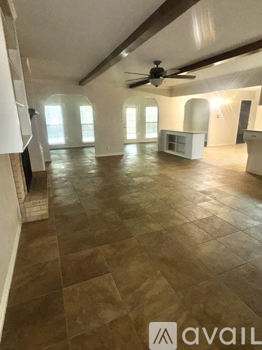 A spacious room with a ceiling fan and large windows.