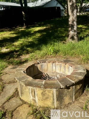A stone fire pit sits in the middle of a grassy area.