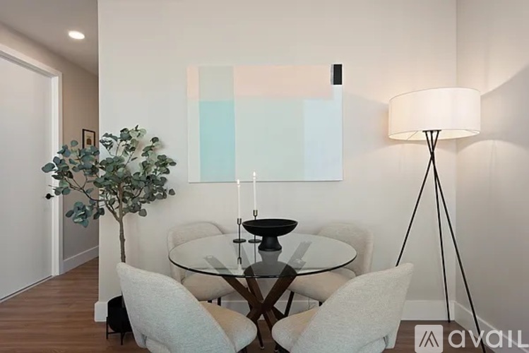 A modern dining room with a glass table and white chairs.