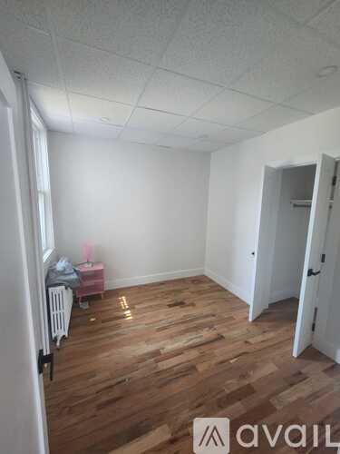 A room with wooden floors and white walls, with a door on the right.