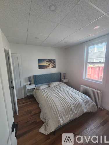 A bedroom with a bed, nightstand, and window.