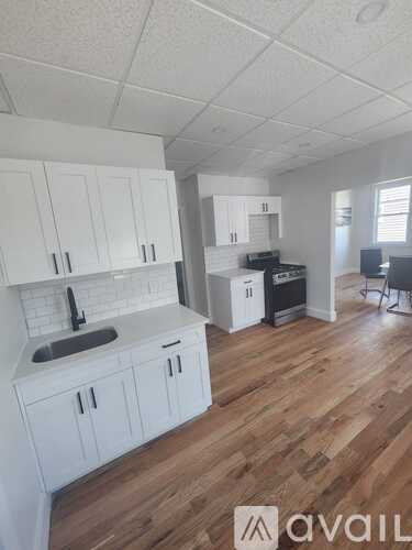 A kitchen with white cabinets and a wooden floor.