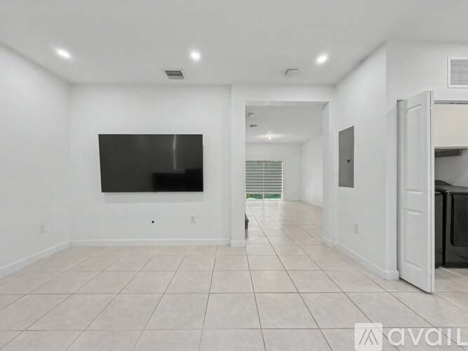 A spacious living room with a flat screen TV mounted on the wall.