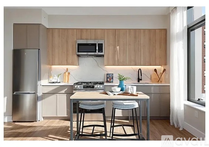 A kitchen with a refrigerator, stove, and a table with two chairs.
