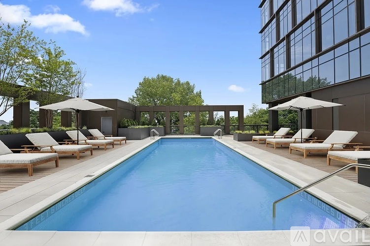 A large outdoor swimming pool surrounded by sun loungers and umbrellas.
