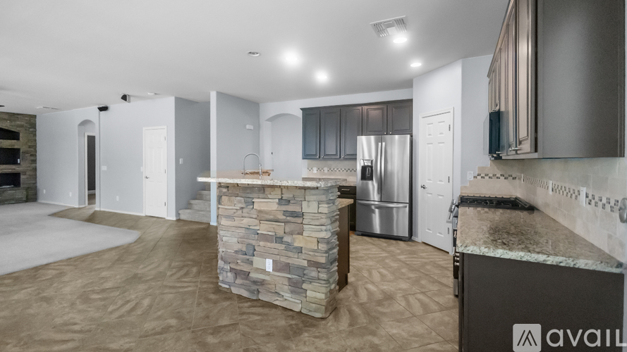 A kitchen area with a stone counter and a refrigerator.