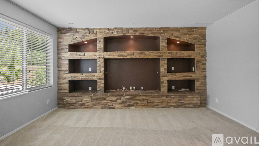 A living room with a stone fireplace and a flat screen TV mounted above it.