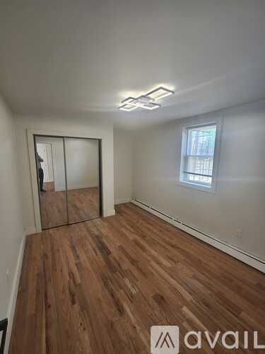 A room with wooden flooring and a window with blinds.