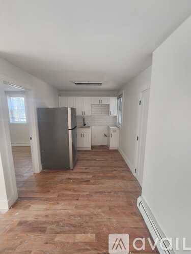 A kitchen with a refrigerator, cabinets, and a window.