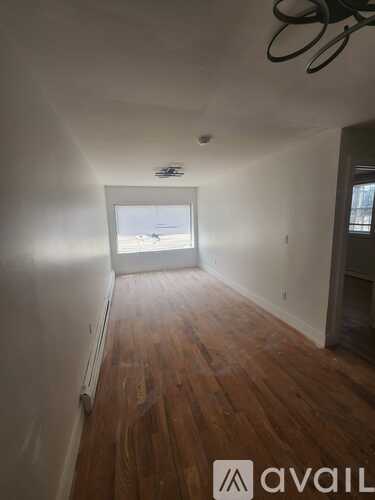 A room with wooden floors and a window overlooking a beach.