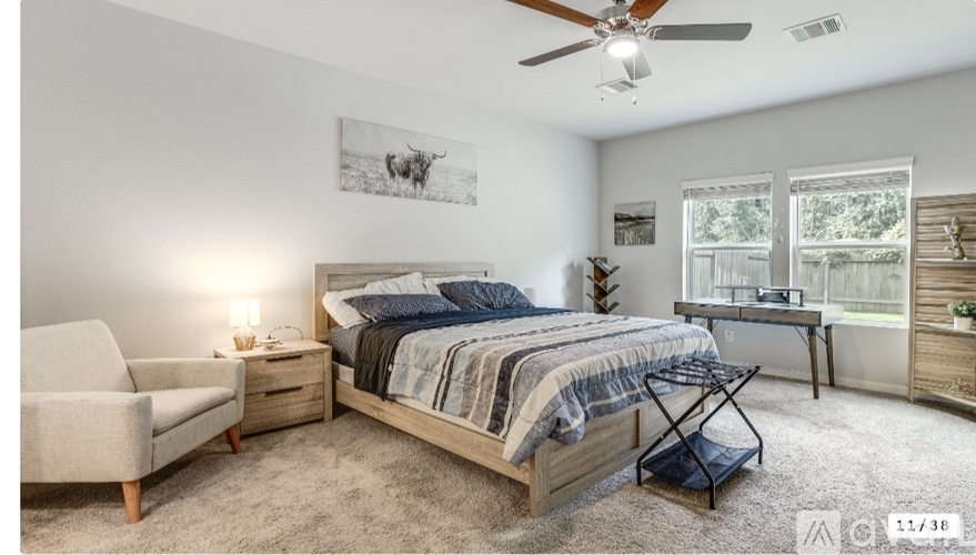 A bedroom with a bed, chair, and a ceiling fan.