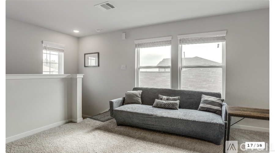 A living room with a grey couch and a window overlooking the water.