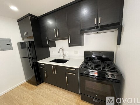 A kitchen with black cabinets and a stove top oven.