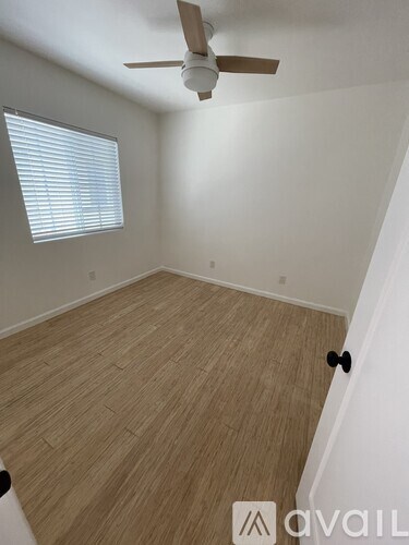 A room with a ceiling fan and a window with blinds.