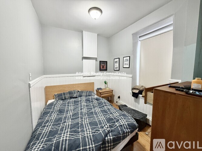 A bedroom with a bed, nightstand, and a window.