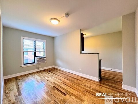 A room with wooden flooring and a window with blinds.