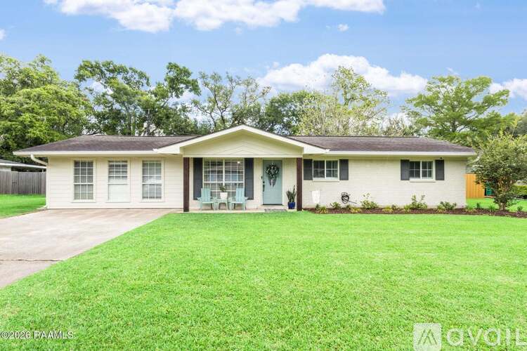 A house with a white exterior and a green lawn in front.