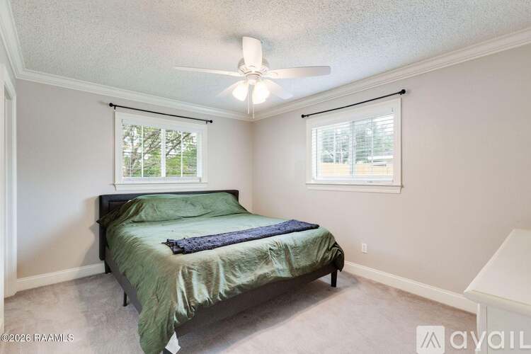 A bedroom with a bed, a window with blinds, and a ceiling fan.