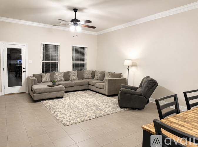 A living room with a grey couch, a black chair, and a wooden table.