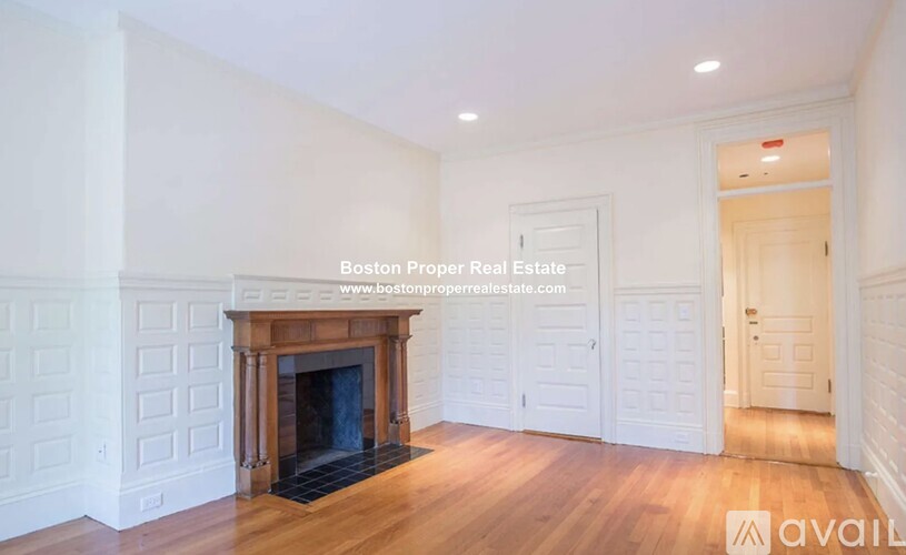 A spacious room with a fireplace and wooden flooring.