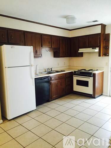 A kitchen with white appliances and brown cabinets.