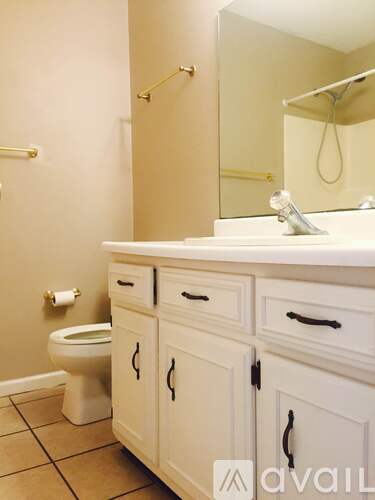 A bathroom with a toilet, sink, and cabinets.