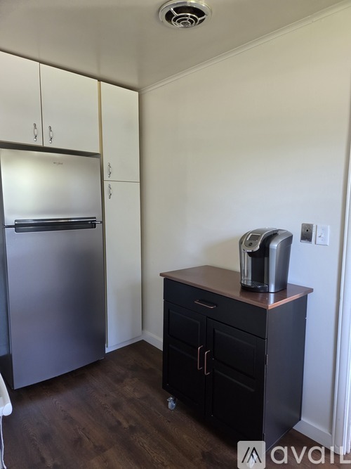 A kitchen with a stainless steel refrigerator and a black countertop with a toaster on it.