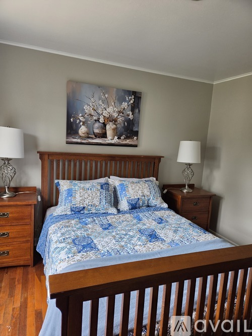 A bedroom with a bed, nightstands, and a painting on the wall.