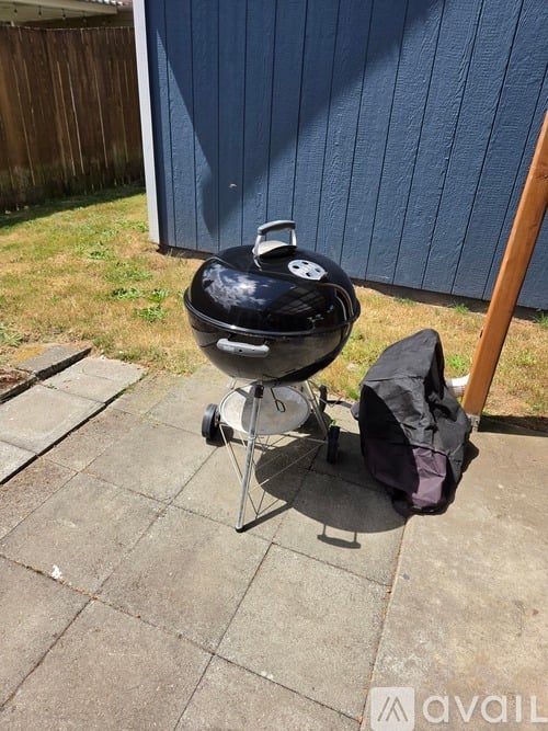 A black barbecue grill with a bag next to it on a patio.