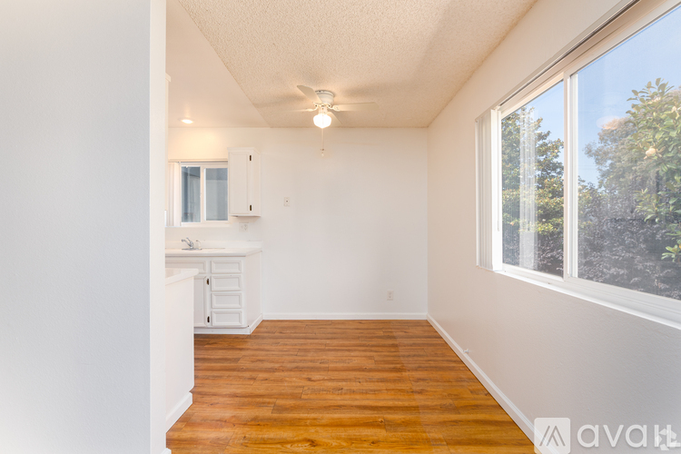 A room with wooden floors and a window overlooking trees.