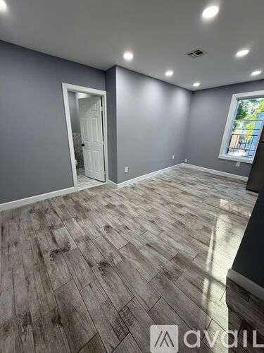 A room with grey walls and wooden flooring with a door and window.
