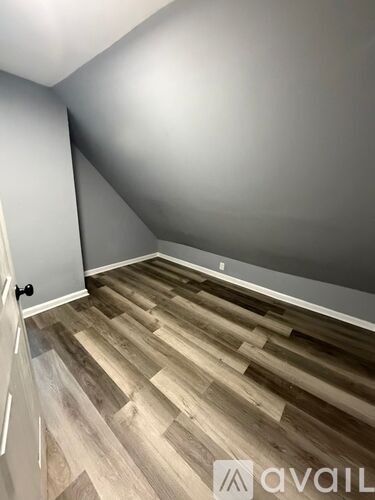 A room with wooden flooring and a door on the left side.