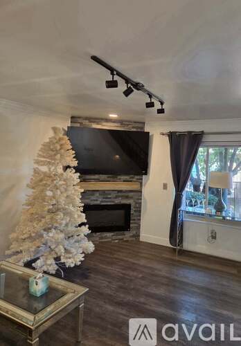 A living room with a fireplace and a Christmas tree.