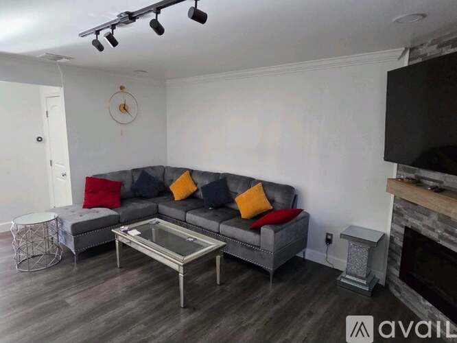 A living room with a grey couch, a glass coffee table, and a fireplace.