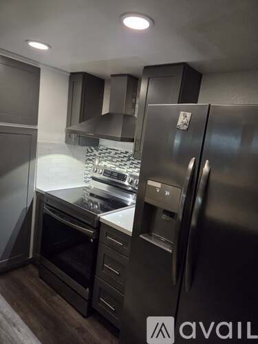 A modern kitchen with stainless steel appliances and a wooden floor.