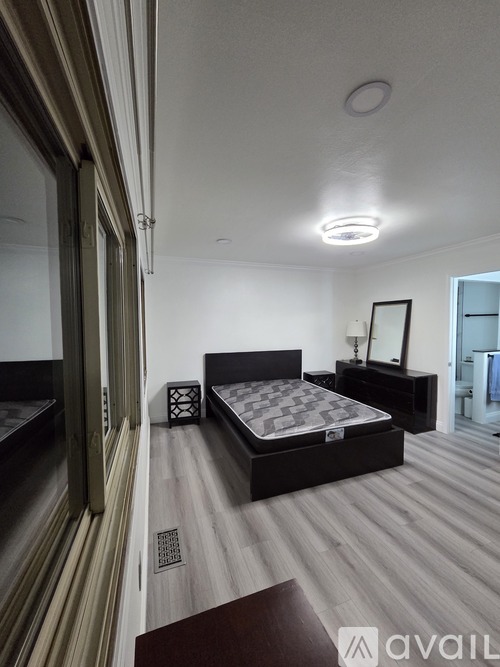 A bedroom with a large bed and a wooden floor.