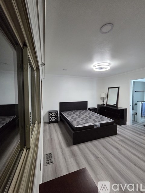 A bedroom with a large bed and a wooden floor.