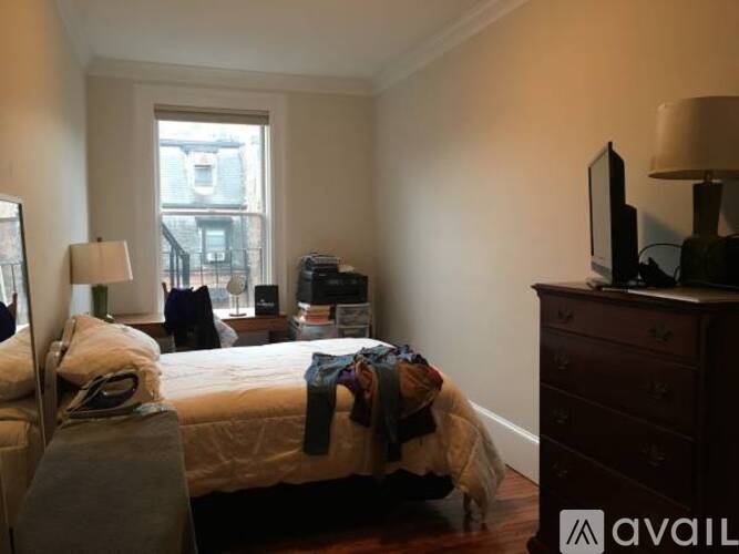 A bedroom with a bed, dresser, and window.