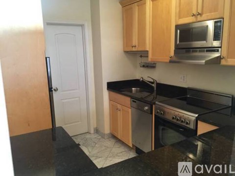 A kitchen with wooden cabinets and black countertops.